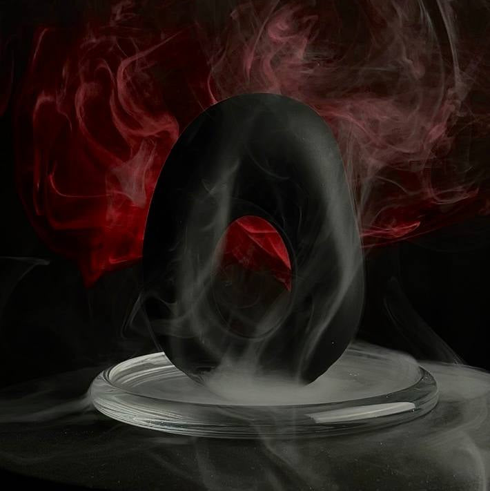 Silhouette of a person in a hooded garment with red fabric, surrounded by swirling smoke on a dark background.